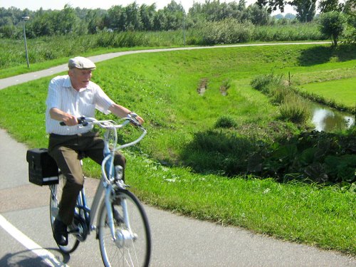 Ein älterer Herr fährt seinen Fahrrad auf einem Radweg auf dem Lande