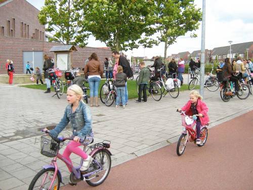 Zwei junge Niederländische Mädchen fahren Fahrräder von der Schule nach Hause